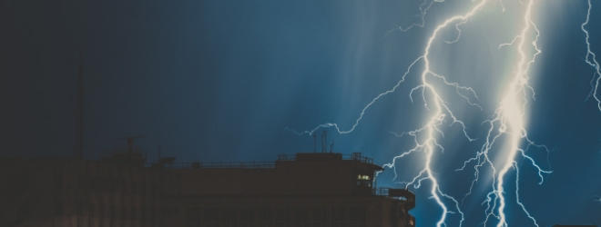 Lightning bolts striking a building over a dark sky