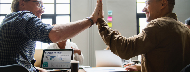 Two men high five each other during a meeting